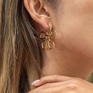 Minimalist gold flower stud earrings in stainless steel on model with a hollow design