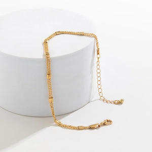 Detail view of gold multilayer chain body jewelry with floral square charms and lobster clasp