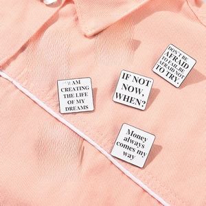 Set of 7 white enamel quote pins with black text on pink denim jacket for women