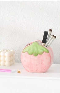 Macro detail of glossy ceramic strawberry holder with vibrant pink finish and green leaf rim
