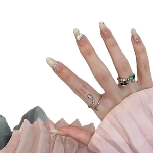 Winter nude press-on nails with silver snake ring and beaded jewelry on a hand