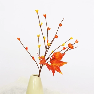 Detail of autumn faux branches with pumpkins, maple leaves and berries in a ceramic vase