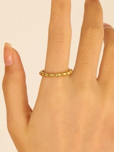 Close-up of a minimalist golden beaded stainless steel ring worn on a finger