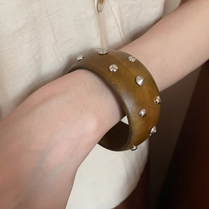 Gros plan d'un bracelet en bois marron avec des clous argentés au design rétro géométrique