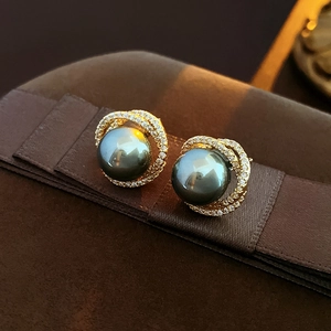 Macro detail of dark grey pearl earrings with gold metal and sparkling zircon stones