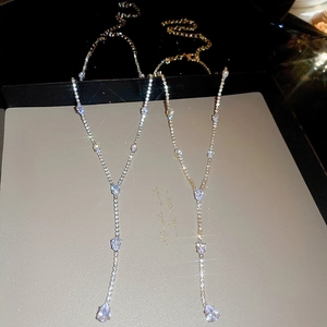Close-up of gold and silver Y-shaped tassel necklaces with sparkling teardrop pendants