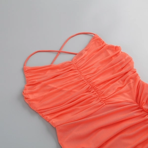 Detail of coral mesh dress featuring criss-cross straps and fine pleated texture