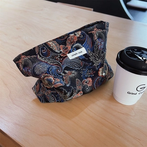 Detail of dark blue brocade cosmetic bag with floral patterns on a wooden table