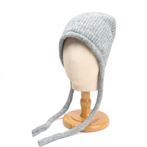 Dettaglio del cappello in maglia grigio chiaro con lunghi paraorecchie e trama a coste