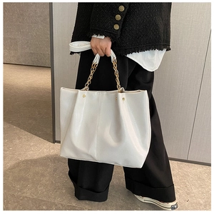 Détail du sac cabas blanc avec poignée en chaîne dorée et texture cuir poli