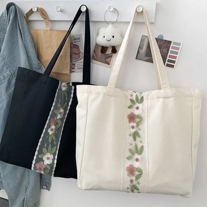 Dettaglio del ricamo floreale e del bordo in pizzo su una borsa tote in tela