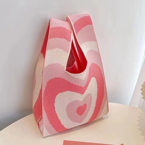 Detail shot of the heart-patterned knitted pink bucket bag on a white tabletop