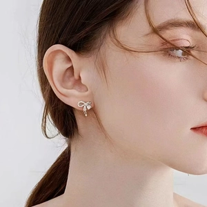Elegant silver bow earrings with micro-set zircons shown on a female model