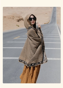 Detail of brown hooded poncho with patterned trim and yellow stitching on desert road