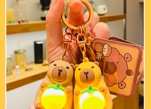 Glow-in-the-dark Capybara keychain set with light-up orange charm in hand display