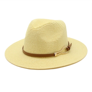 Detail of wide brim straw Panama hat featuring brown leather band and gold metal buckle