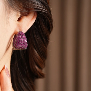 Close-up of pavé set pink zircon C-shaped hoop earrings on female model ear