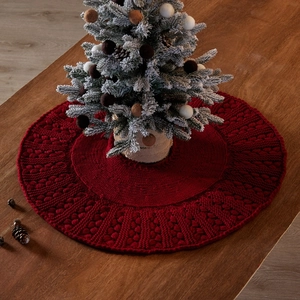 Red knit Christmas tree skirt with woven texture on wooden tabletop for festive decor