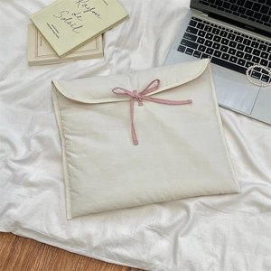 Dettaglio della borsa porta PC trapuntata color crema con fiocco rosa e decorazioni scrivania
