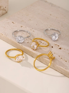 Close-up of luxury oval zircon rings in gold and silver on a textured stone base