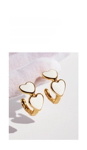 Detail of vintage double heart earrings with white enamel and golden metal base texture