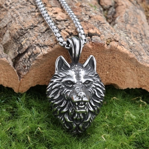 Detailed macro view of silver wolf head pendant on wood block with square link chain