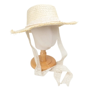 Detail of woven straw hat with delicate white lace trim and long ribbons on mannequin