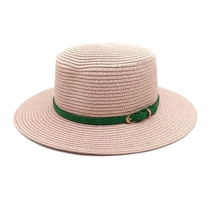 Détail de la texture d'un chapeau en paille avec ruban en cuir vert et boucle dorée