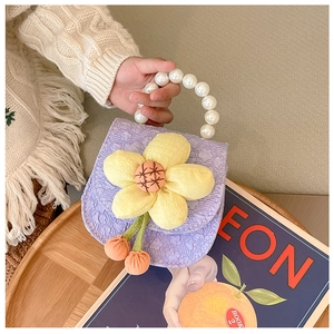 Close-up of purple ruffled child's saddle bag with yellow 3D flower and pearl handle