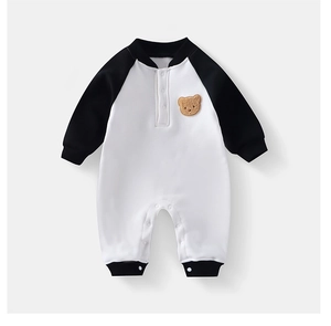 Detail eines Baby-Stramplers mit Kontrast-Raglanärmeln und süßem Teddybär-Aufnäher
