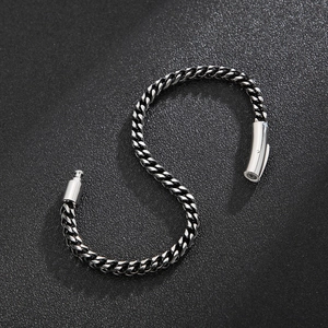 Detail of silver titanium steel dragon bone chain bracelet with cylindrical buckle on black background