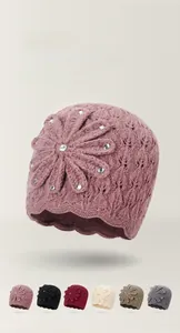 Gedetailleerd beeld van handgebreide muts met strass bloemen in zes zachte kleuren