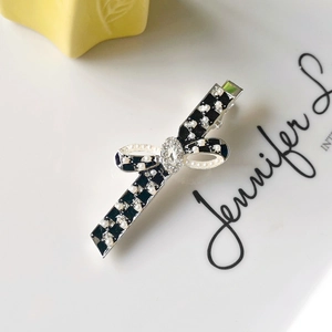 Detail of checkered bow hair clip with pearls and crystal on a white display tray