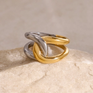 Two-tone intertwined 18k gold and silver stainless steel ring on a natural stone base