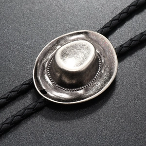Close-up of vintage silver cowboy hat metal pendant and black braided bolo tie leather cord