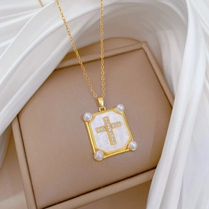 Detail of luxury gold cross necklace with pearl and shell inlay on silk background