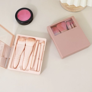 Detail of 5-piece portable makeup brush set with mirror inside a pink storage case