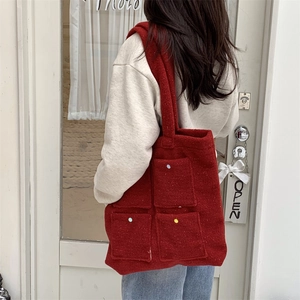 Detail of burgundy felt tote bag with multi-pockets and colorful buttons on wide strap