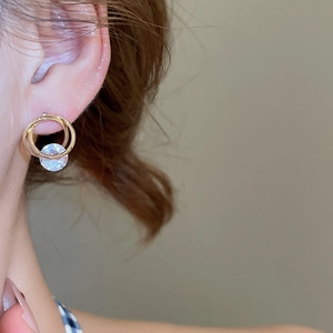 Detailed view of elegant gold spiral earrings with zircon on a model for luxury look