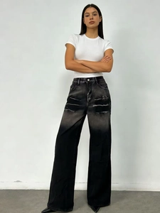 Detailed shot of gray gradient washed denim jeans with ripped knees and wide-leg cut