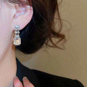 Close-up of silver square crystal drop earrings worn by a model for a vintage look