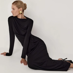 Detail of elegant black bodycon dress featuring side ruching and mock neck draping