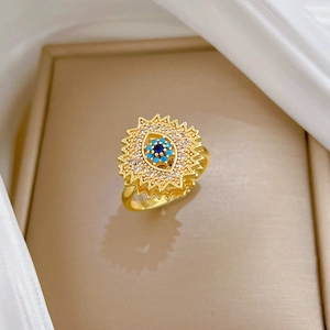 Rotating gold evil eye ring with blue stones and crystals on soft silk background