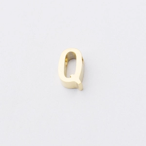 Macro detail of polished gold-finished alphabet Q bead for jewelry making
