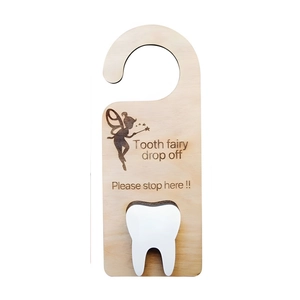 Macro detail of a wooden tooth fairy door hanger with a white pocket and fairy engraving