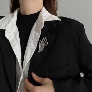 Polished silver hand-shaped brooch pinned to a black suit lapel for fashion styling