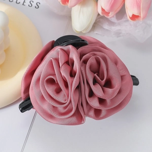 Close-up of pink silk double rose hair claw clip with satin texture and black grip