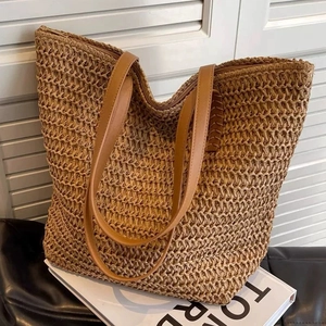 Detail of handwoven straw tote bag with synthetic leather handles and zipper closure