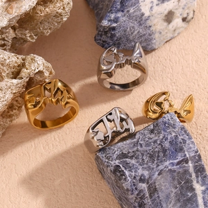 18K gold plated stainless steel rings with FLY heart design on a textured surface