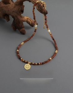 Detail of beaded necklace with freshwater pearls and evil eye charm on wood background
